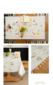Detail of embroidered green leaf vines and off-white tassel edges on linen tablecloth