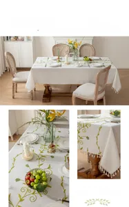 Detail of green rose floral embroidery and fringe tassel on beige cotton linen tablecloth