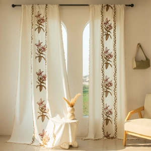 Dettaglio del ricamo floreale e delle nappe su tende di lino beige in stile americano