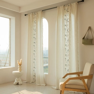 Detail of cream fabric curtain with floral embroidery and elegant fringe edge