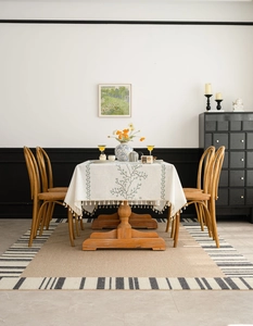 Detail view of cream tablecloth with blue vine embroidery and elegant tassel edges