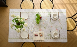 Detail of floral embroidery on a grey linen tablecloth with elegant tassels