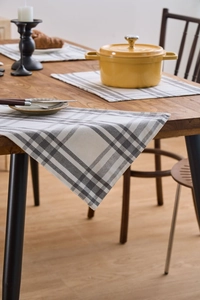 Close-up of Nordic grey and white checkered fabric placemat on a solid wood table