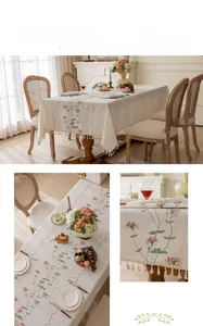 Detail of floral embroidery and cream tassels on a French style linen tablecloth