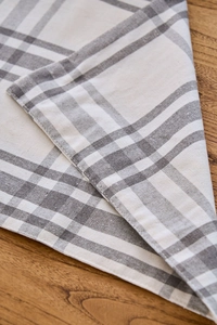 Detail showing the fine stitching and grey-white checkered texture of the cotton linen placemat
