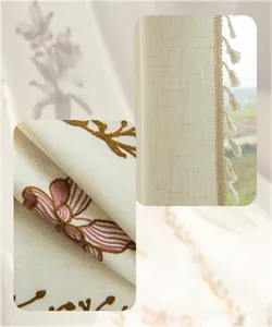 Dettaglio ricamo floreale su tenda beige semi-trasparente con nappe decorative