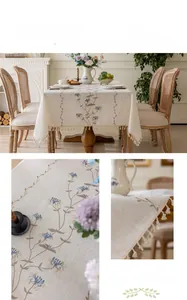 Detail of blue floral embroidery and beige tassels on a cotton linen rectangular tablecloth