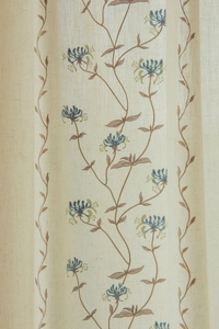 Detailed close-up of beige linen fabric with elegant blue floral embroidery and leaf patterns