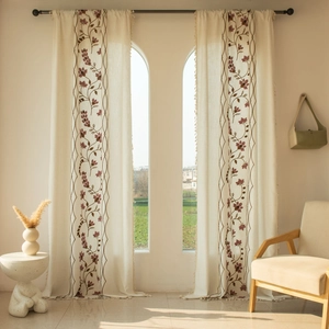 Detail of floral embroidery and fringe trim on semi-sheer beige cotton linen curtains