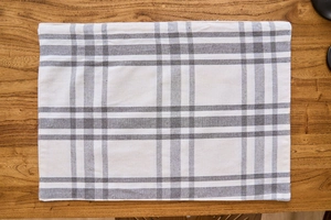 Vertical top view of gray and white checkered fabric placemat on a wooden table surface