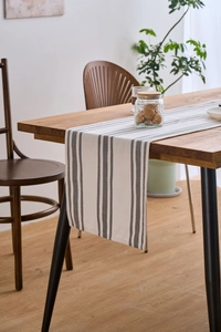 Close-up of Nordic table runner with grey stripes draped over a wooden table edge