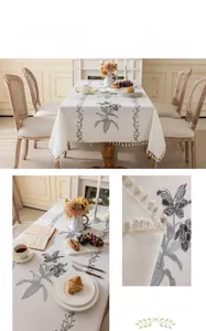 Close-up of lily embroidery and fringe tassels on a cream cotton linen tablecloth