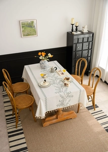 Detailed close-up of linen tablecloth featuring vine embroidery and elegant tassel edges