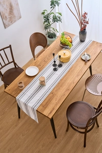 Close-up of modern striped table runner in beige and grey linen blend on wooden dining table