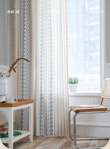 Detail of bohemian cotton linen curtain with blue geometric embroidery and tassels