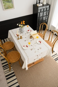 Detail of cream rectangle tablecloth with flower embroidery and elegant cream tassels