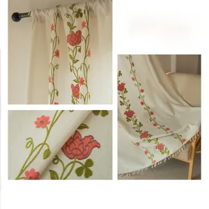 Dettaglio del ricamo a rose su tenda di lino beige con bordo a frange