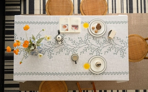 Close-up of elegant green vine embroidery and berry patterns on textured linen tablecloth