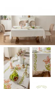 Detail of French vintage tablecloth featuring pink lily embroidery and cream fringe tassels