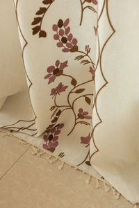 Detailed close-up of floral embroidery and beige tassels on semi-sheer cotton linen curtain