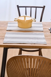 Close-up of gray and white striped fabric placemats on a rustic wooden dining table