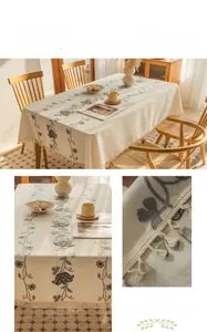 Close-up of floral embroidery and delicate fringe on a cream linen-cotton tablecloth