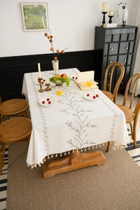 Detail of lilac embroidery and beige tassels on a cotton linen rectangular tablecloth