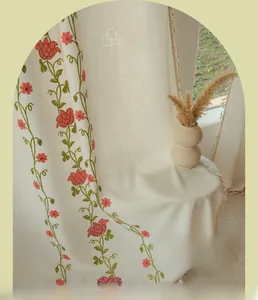 Close-up of beige embroidered floral curtains with elegant tassel fringe and vine patterns