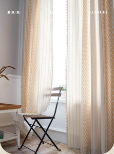 Detail of yellow geometric pattern and beige tassels on bohemian semi-sheer curtains