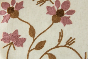 Detail of floral embroidery on off-white linen fabric with purple flower petals