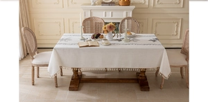 Détail de nappe à pompons crème avec broderie symétrique d'oiseaux et de feuilles gris foncé