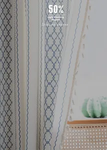 Detail of blue geometric embroidery and tassels on semi-sheer cotton linen curtain