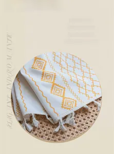 Detail of yellow geometric pattern on beige linen fabric with white tassels for curtains