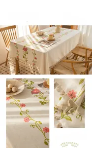 Detailed close-up of rose flower embroidery and tassel edge on cream linen tablecloth