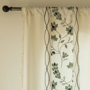 Detail of floral embroidery and elegant tassel fringe on semi-sheer beige curtains