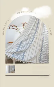 Detail showing blue geometric embroidery and fringe trim on a beige cotton linen curtain