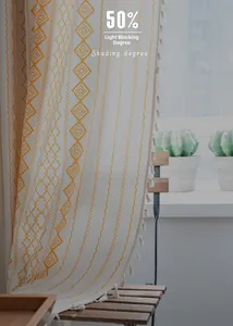 Detail of beige semi-sheer curtain featuring yellow geometric embroidery and white tassels
