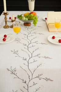 Detail of embroidered lilac floral pattern on beige linen tablecloth with rustic decor