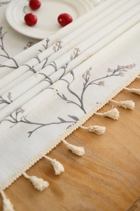 Detail of cream table runner with vintage floral embroidery and elegant tassels