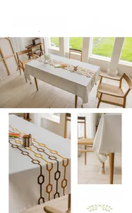 Detail of cream rectangular tablecloth featuring orange chain embroidery and tassels