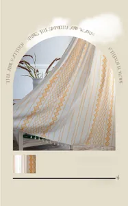 Detail of yellow geometric patterns and tassels on a knit throw blanket for home decor