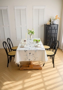 Close-up of Nordic style linen tablecloth with blue floral embroidery and tassel fringe