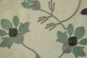 Detail of floral embroidery on off-white linen fabric with elegant textured patterns