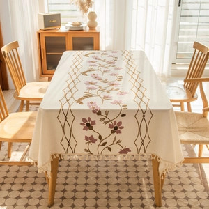 Detailed embroidery of floral patterns and fringe on beige linen rectangular tablecloth