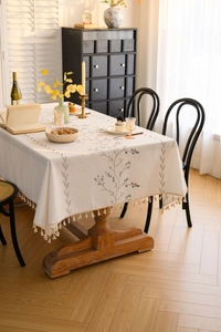 Detail view of floral embroidery and beige tassels on a cotton linen tablecloth