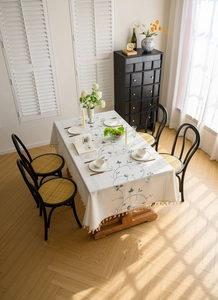 Detail of floral embroidery and fringe tassel on cream linen tablecloth for dining tables