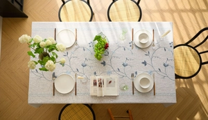 Detailed embroidery of blue floral patterns on cream cotton linen tablecloth