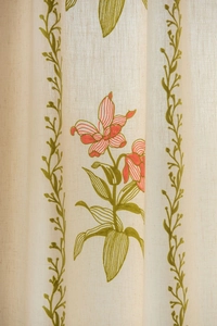 Dettaglio di tenda in lino beige con ricami floreali rossi e bordi di vite verde