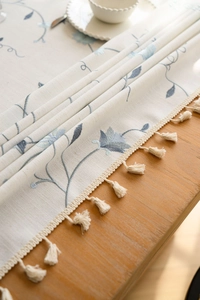 Close-up of blue floral embroidery and fringe edge on linen tablecloth fabric
