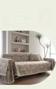 Detail of pink floral jacquard sofa cover with fringe trim on a textured throw blanket